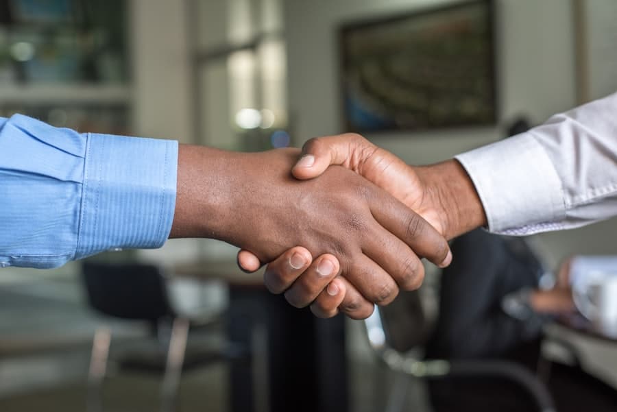 Two professionals shaking hands in an office after a successful hire
